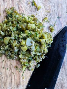 Chopped up cornichons on a wooden board