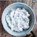 A bowl of tartar sauce on a wooden board