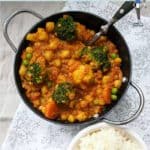 A bowl of chickpea and lentil curry with a bowl of white rice