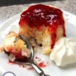 A pear sponge topped with raspberry jam on a white plate