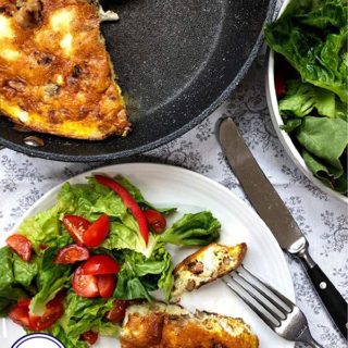 A frittata in a pan with a plate of salad and frittata to the side.