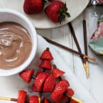 Strawberry kebabs on a board with chocolate dipping sauce