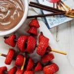 Some strawberry kebabs next to a box of mikado sticks