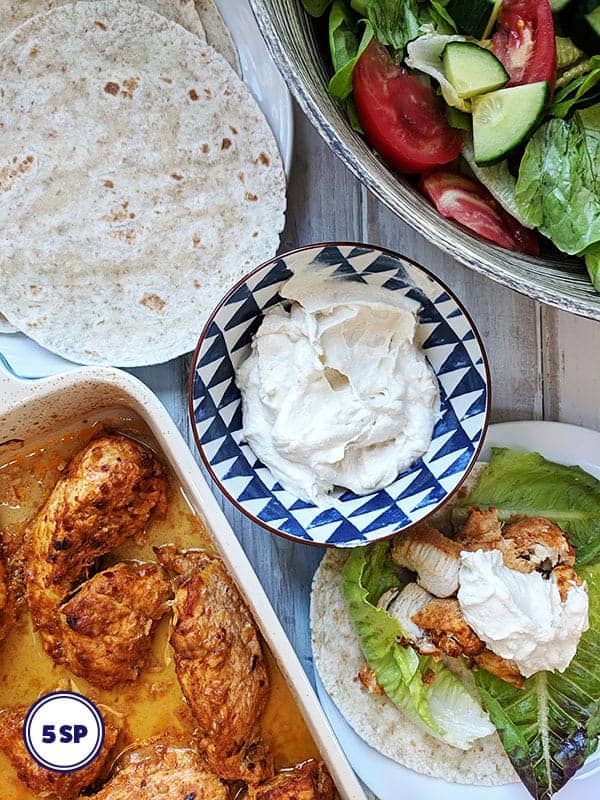 A dish of shawarma chicken with flatbreads and salad