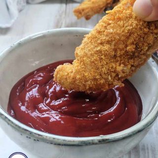 A Chicken tender being dipped into sauce