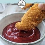 A chicken tender being dipped into sauce