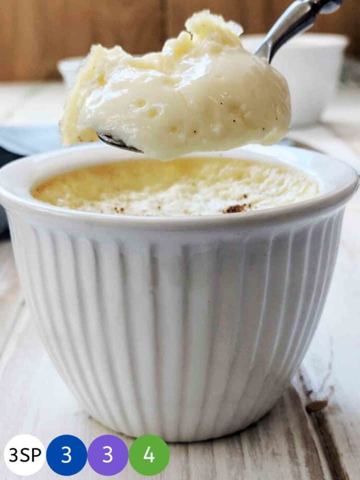 Some baked egg custard being spooned from a ramekin