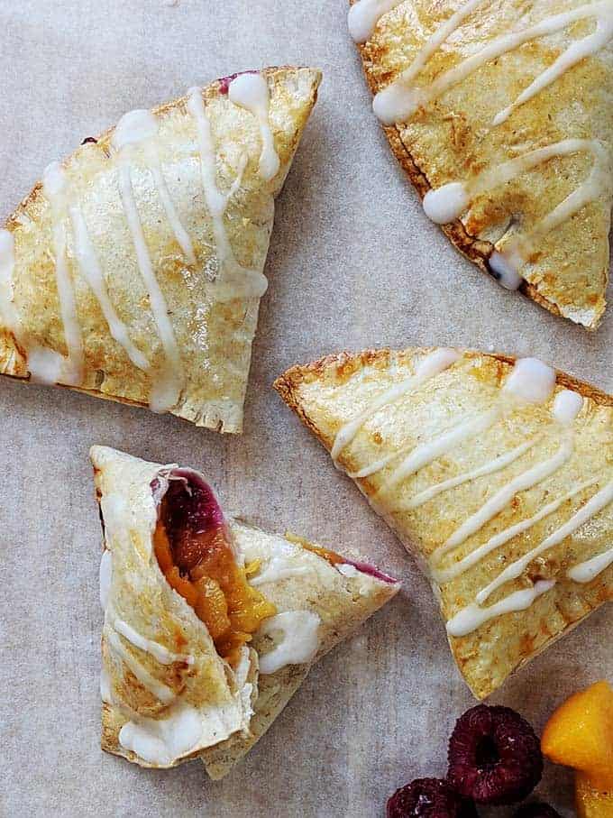 Peach pies on a sheet of baking parchment