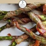 A plate of Parma Ham wrapped asparagus on a white plate