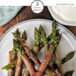 A plate of proscioutto wrapped asparagus on a white plate