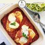 A casserole dish of chicken parmesan on a white table