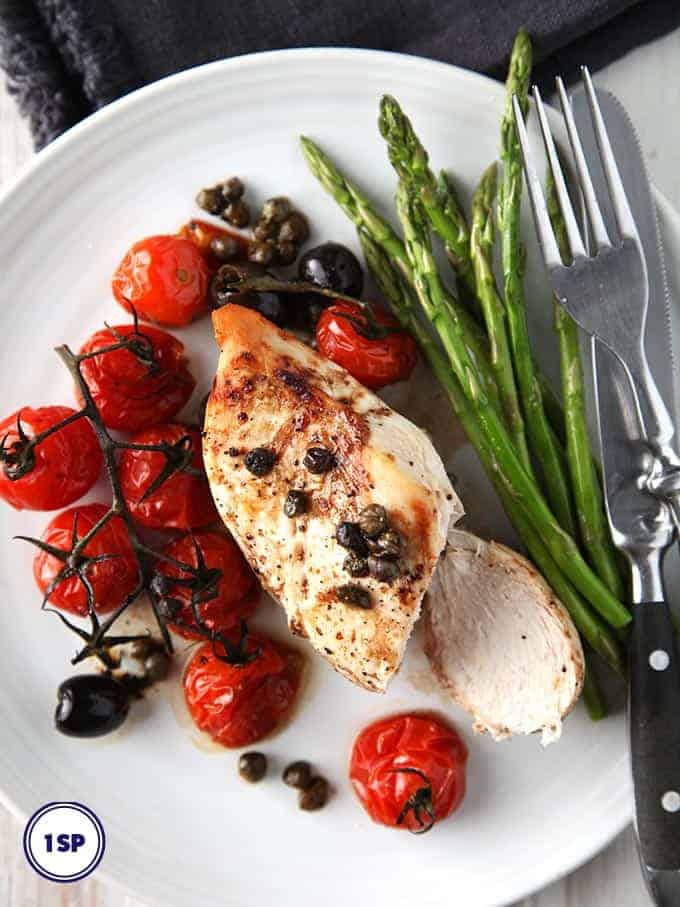 Balsamic chicken on a white plate with a side of asparagus spears