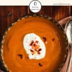 A bowl of curried pumpkin soup on a wooden table.