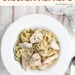 A white bowl of chicken Alfredo on a white table