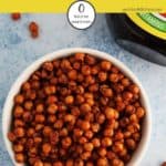 Some marmite chickpeas in a white bowl with a pot of marmite to the side