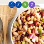 A bowl of three bean salad with a wooden serving spoon