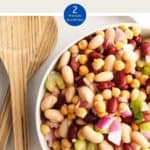 A bowl of three bean salad with a wooden serving spoon