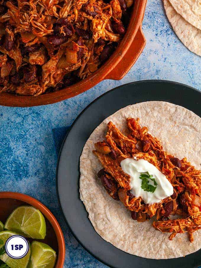 A dish of Mexican Mole next to a plate with tortilla