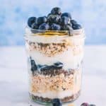 A jar layered with oats, chia seeds, blueberries and yogurt.
