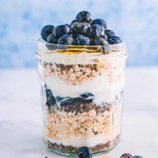 A jar layered with oats, chia seeds, blueberries and yogurt.