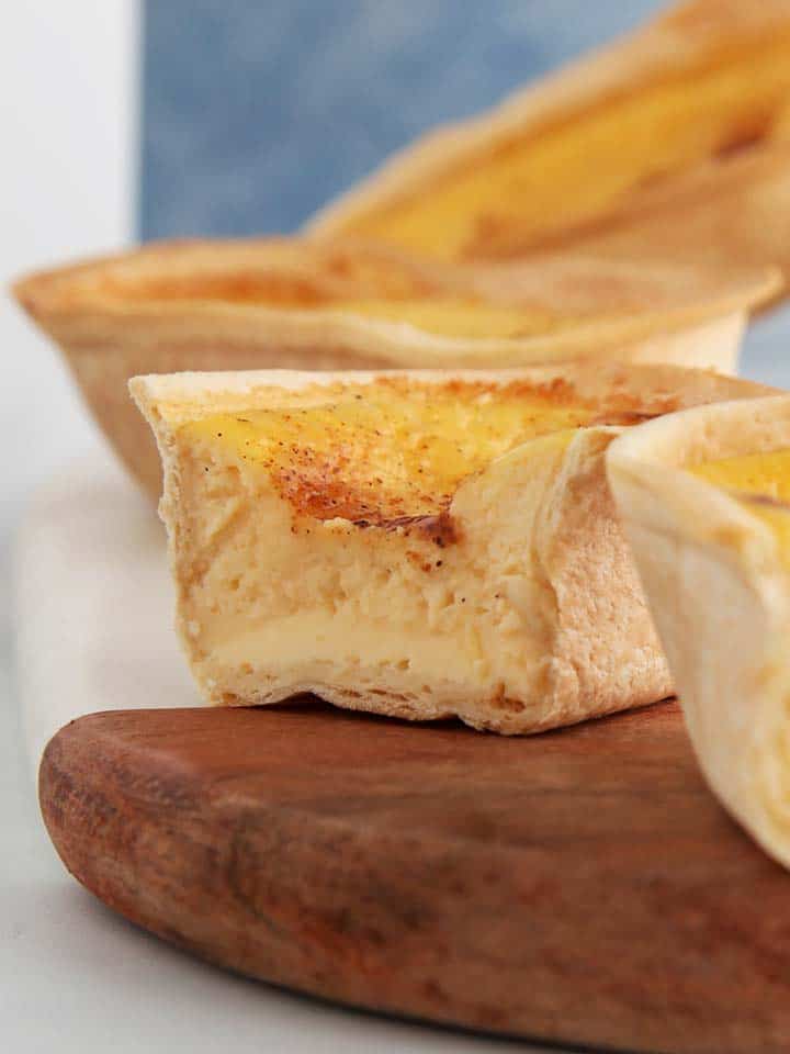 A close up picture of a custard tart on a wooden board