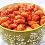 A green bowl full of red baked beans