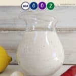 A jug full of a creamy salad dressing