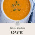 A white bowl full of roasted carrot & ginger soup on a white table