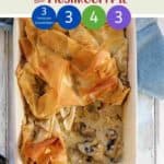 A dish of chicken leek & Mushroom pie on a white table with a blue napkin