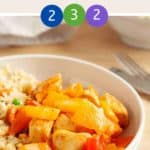 A white bowl of sweet & sour chicken with cauliflower rice on a wooden table