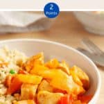 A white bowl of sweet & sour chicken with cauliflower rice on a wooden table