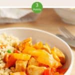 A white bowl of sweet & sour chicken with cauliflower rice on a wooden table