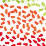 Red, green and orange gummy bears on a white table