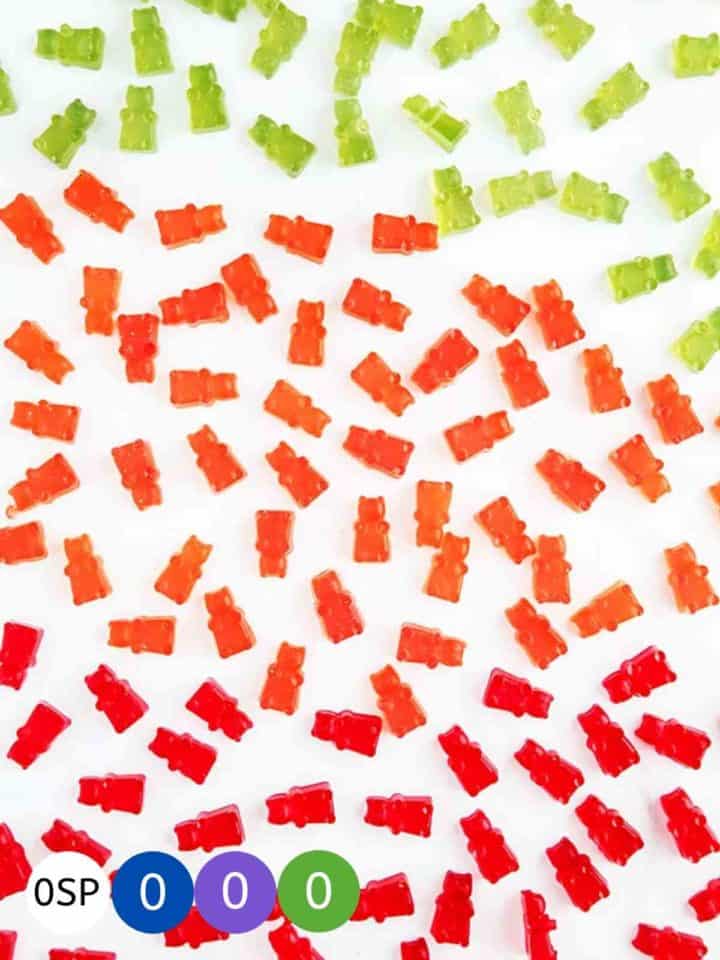 Red, green and orange gummy bears on a white table