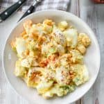A white ceramic bowl full of egg salad on a wooden table