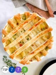 A dish of chicken pot pie with a pastry latticed top and a sprig of thyme