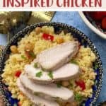 A decorative blue bowl full of couscous salad with sliced chicken on top