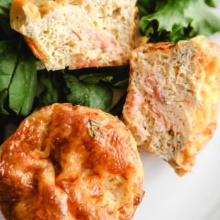 Two smoked salmon breakfast muffins on a bed of green lettuce.