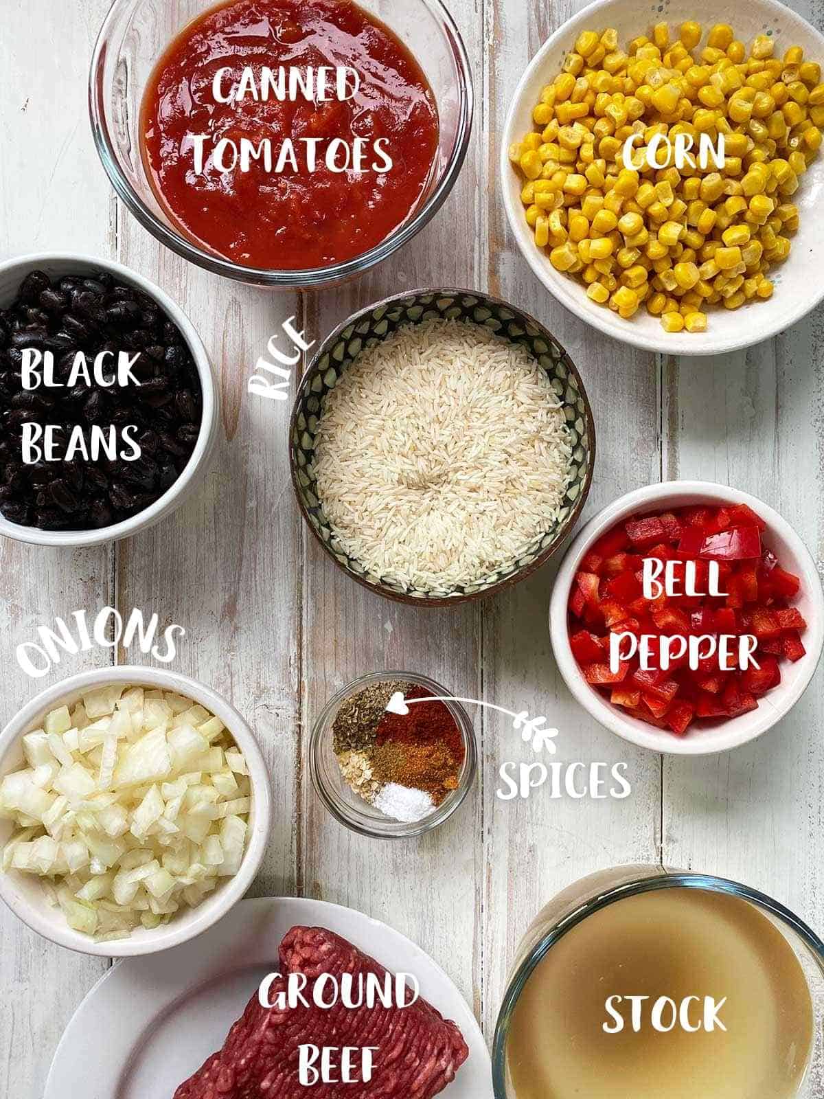 All of the ingredients to make burrito bowl in small bowls with text description.