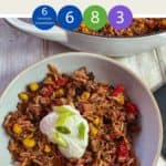 A bowl of burrito mixture topped with yogurt and chopped spring onion on a white table & text overlay 'Weight Watchers Burrito Bowl'.