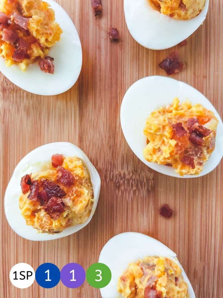 5 cheese and bacon stuffed eggs on a wooden board.