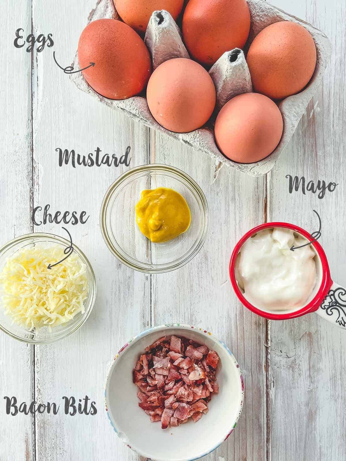 Ingredients that are used for deviled eggs on a white wooden table with label text overlay.