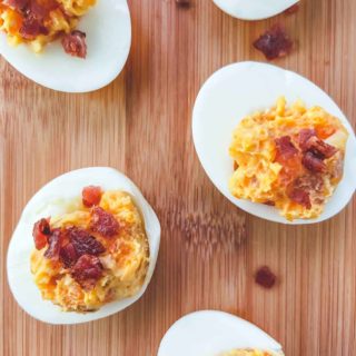 5 cheese and bacon stuffed eggs on a wooden board.