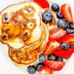 A white plate with pancakes and berries and topped with syrup and graphics showing the Weight Watchers smartpoint values.