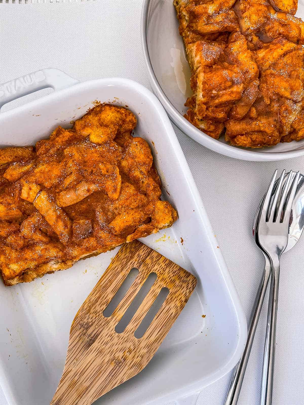 A dish of french toast casserole with a wooden spatula.