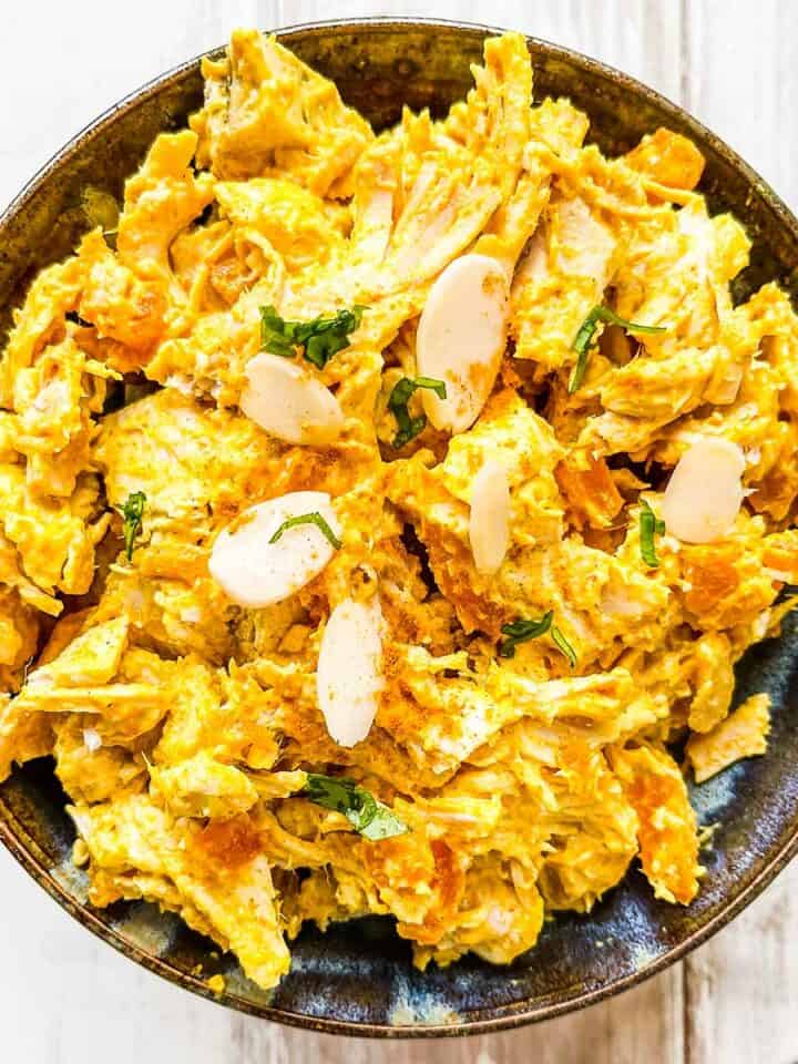 A dish of curried turkey salad on a white table.