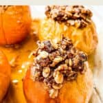 A close up picture of a baked apple topped with an oat mixture.