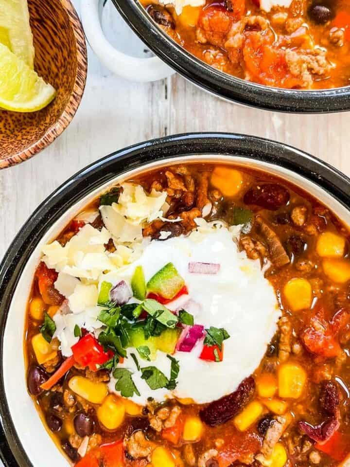 Two bowls of Weight watchers taco soup topped with yogurt and herbs.
